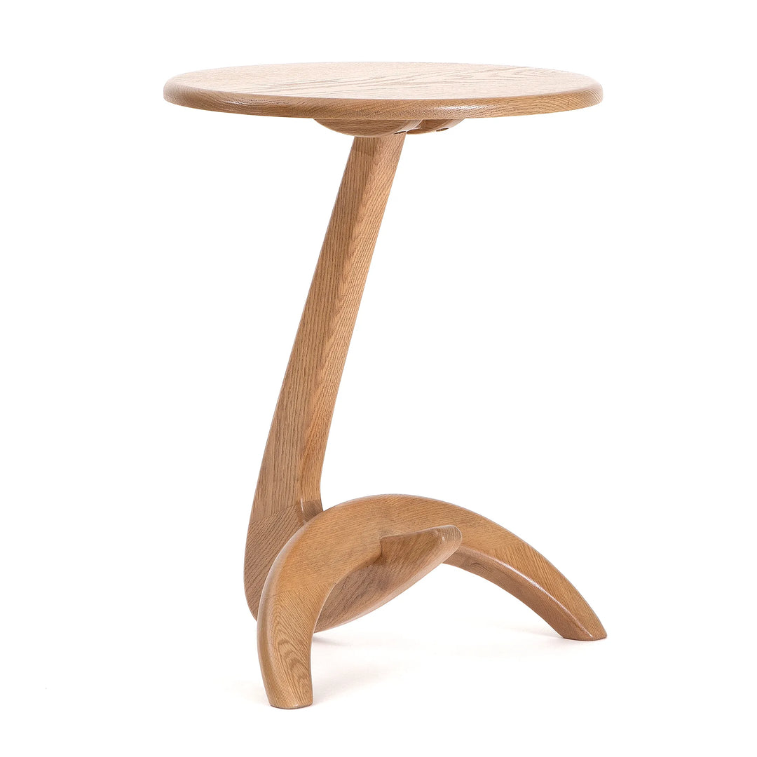 A side table made of solid oak with a biomorphic shape, featuring a curved base and a rounded top.
