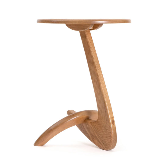 A side table made of solid oak with a biomorphic shape, featuring a curved base and a rounded top.